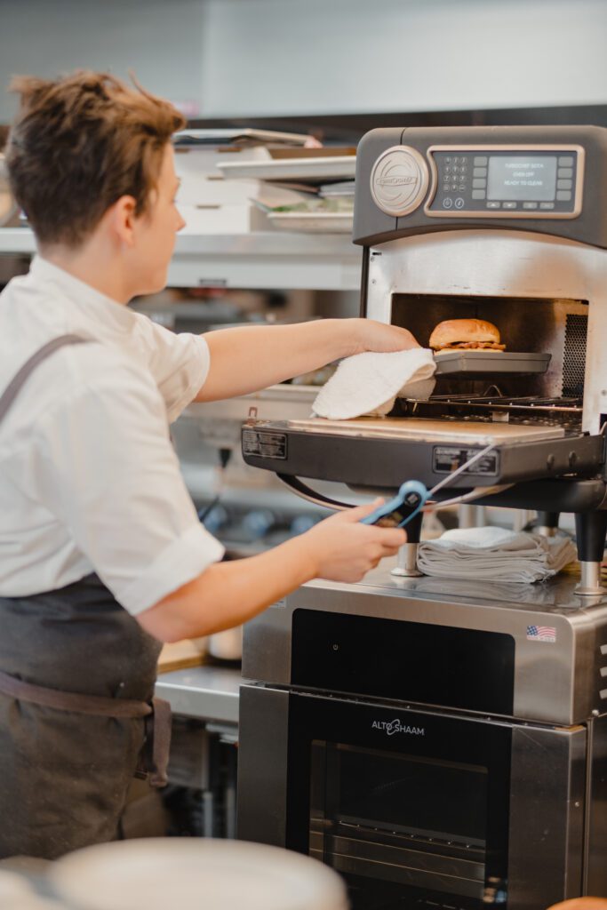 Foodservice professional placing a sandwich in a commercial oven